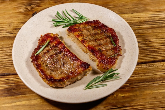 Gegrilde varkenssteaks met rozemarijn op houten tafel