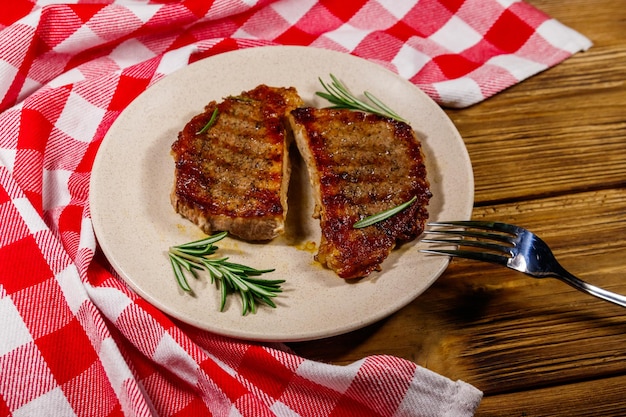 Gegrilde varkenssteaks met rozemarijn op houten tafel