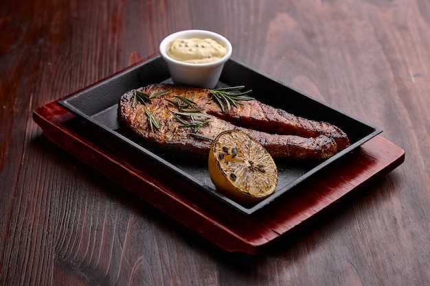 Gegrilde vis met saus op een donkere houten tafel