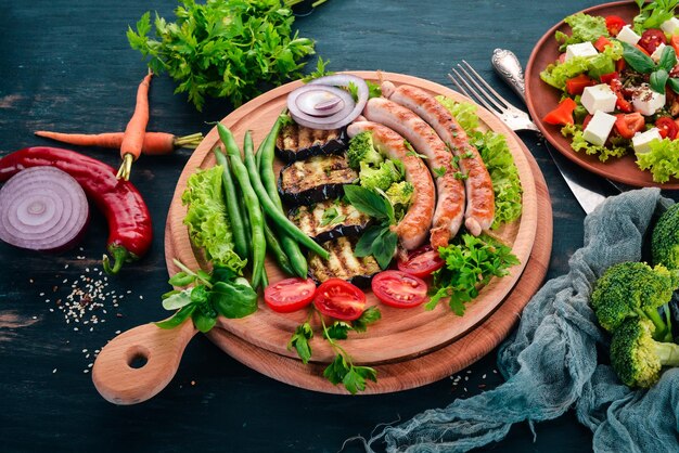 Gegrilde worst met auberginebonen en tomaten op het bord Gezonde voeding Op een zwarte houten tafel Bovenaanzicht Vrije ruimte voor tekst