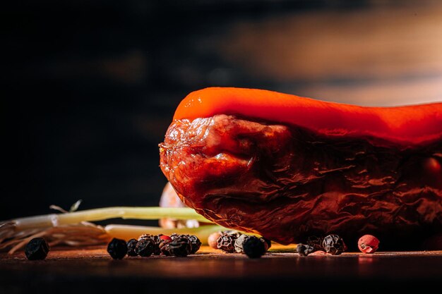 Gegrilde worst op een donkere achtergrond op een houten ondergrond met kruiden en saus