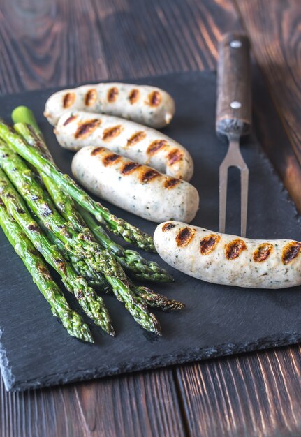 Gegrilde worstjes met asperges op stenen bord