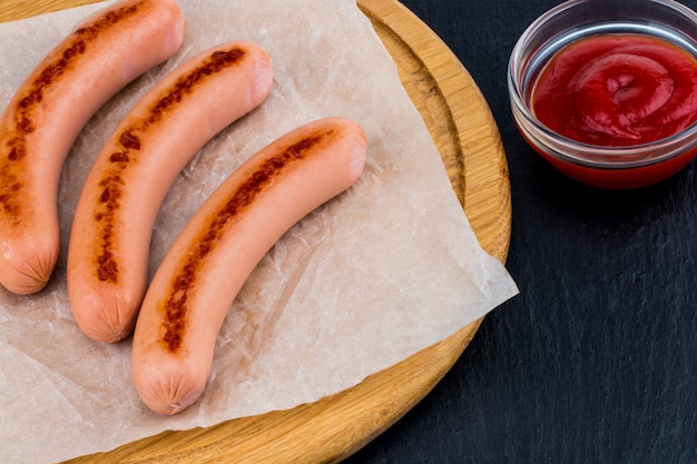 Gegrilde worstjes met saus op een houten bord