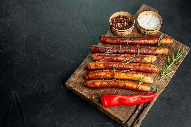 gegrilde worstjes op een snijplank met kruiden en rozemarijn op een stenen tafel met kopie ruimte voor uw tekst