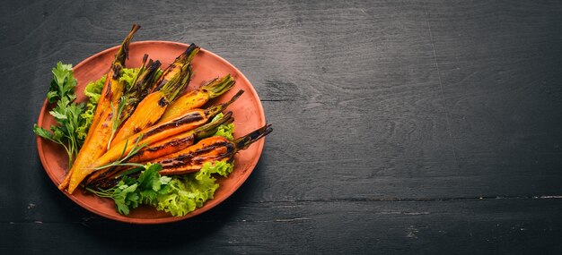 Gegrilde wortel in een bord met groenten Op een houten achtergrond Bovenaanzicht Kopieer de ruimte