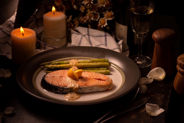 Gegrilde zalm en asperges op plaat met een glas witte wijn tijdens het diner