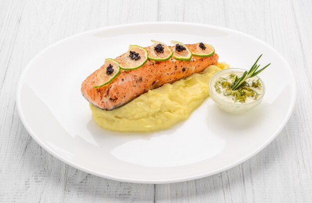 Gegrilde zalm, gekookte aardappelen en groenten op een witte plaat