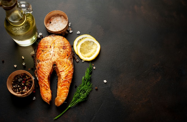 gegrilde zalm steaks met specerijen, kruiden, zout en citroen op een stenen achtergrond met kopie ruimte voor uw tekst