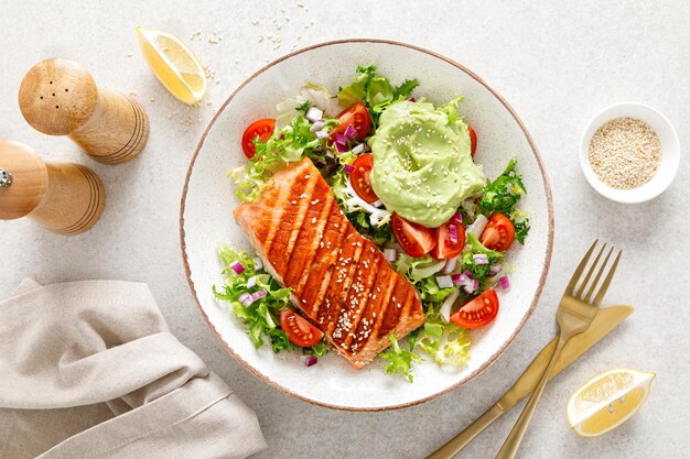 Gegrilde zalm visfilet en verse groene sla groente tomatensalade met avocado guacamole bovenaanzicht