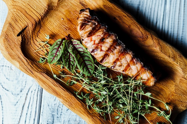 Gegrilde zalm visfilet met groene salade op de houten snijplank close-up