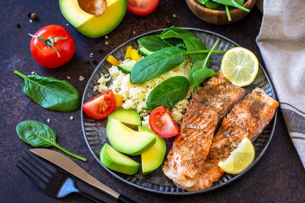 Foto gegrilde zalmfilet close-up met couscous salade verse groenten en avocado op donkere achtergrond