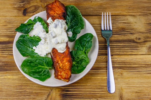 Gegrilde zalmfilet met spinazie en tartaarsaus op houten tafel bovenaanzicht