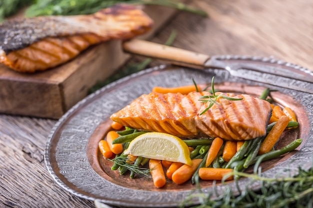 Foto gegrilde zalmfilet sesamzaadjes kruidendecoratie op vintage pan of zwarte leisteen plank