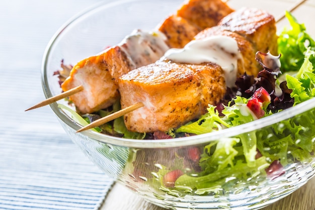 Gegrilde zalmspiesjes met zomersla salat granaatappelpitjes olijfolie en dressing. gezond visvoer met groente en fruit.