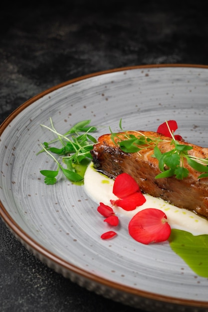 Gegrilde zalmsteak met kruiden en een takje doperwten op een donkere stenen tafel