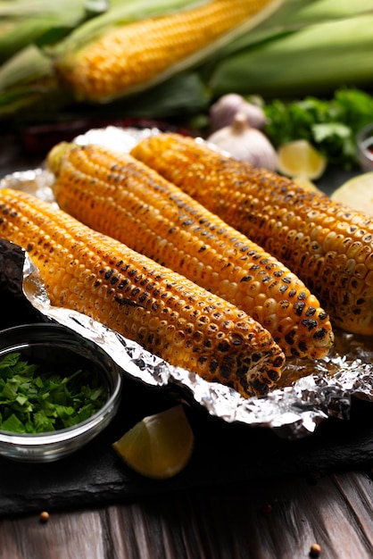 Foto gegrilleerde maïs op de kolf in tinfolie op de keukentafel gezonde glutenvrije voedsel achtergrond