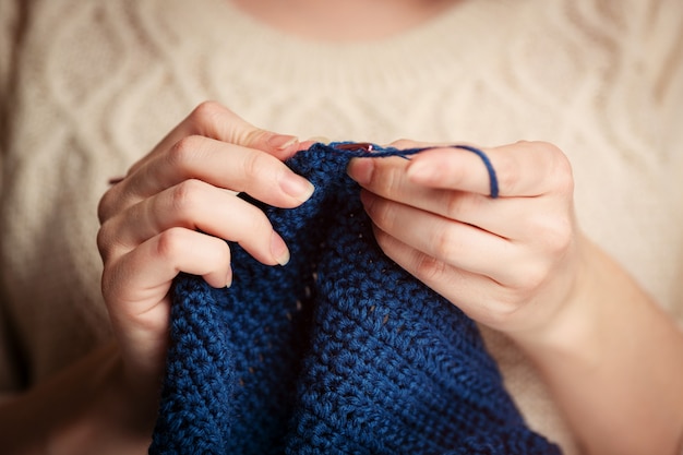 Gehaakt. Vrouw haak donkerblauw garen. Close-up van de handen.