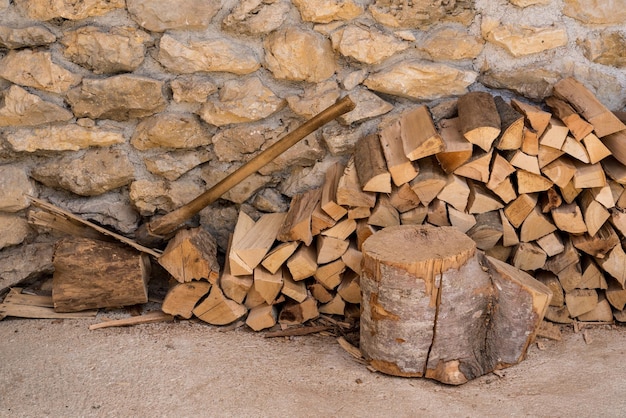 Gehakt hout en bijl gestapeld tegen de stenen muur van een rustieke boerderij