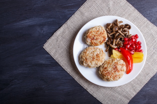 Gehaktballen met rijstpaddestoelen, paprika&#39;s en granaatappelzaden op zwarte houten.