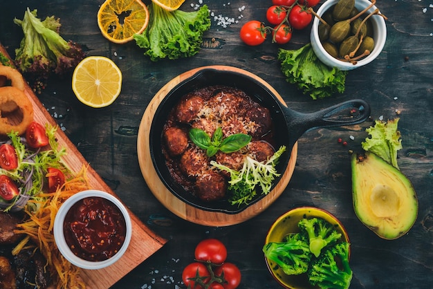 Gehaktballen met tomatensaus en groenten in een koekenpan Op een houten tafel Bovenaanzicht Kopieer de ruimte