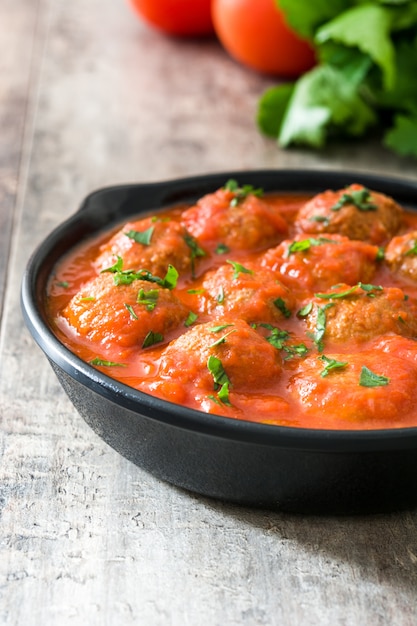 Gehaktballen met tomatensaus in ijzeren koekenpan op houten tafel