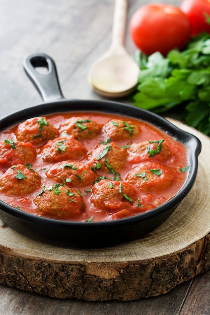 Gehaktballen met tomatensaus in ijzeren koekenpan op houten tafel