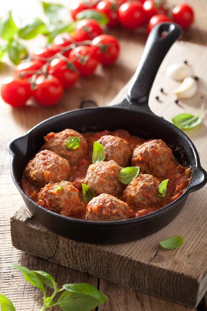 Foto gehaktballen met tomatensaus in zwarte pan