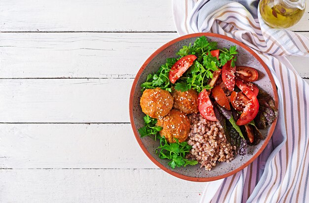 Gehaktballen, salade van tomaten en boekweit PAP op witte houten tafel. Gezond eten.