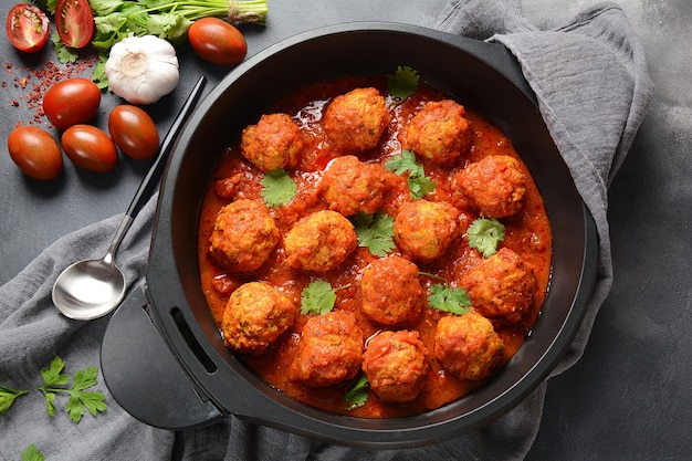 Gehaktballetjes in zoete tomatensaus met kruiden geserveerd in een koekenpan