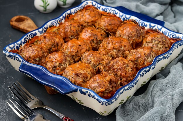 Gehaktballetjes in zure room en tomatensaus in keramische vorm tegen een donkere achtergrond, horizontale oriëntatie