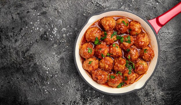 Gehaktballetjes met tomatensaus in koekenpan op lichte achtergrond Lange banner formaat bovenaanzicht