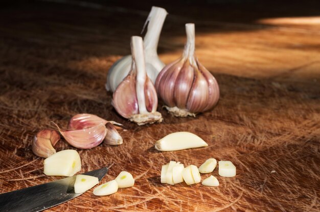 Gehakte knoflook naast en rond mes en hele ongeschilde knoflookteentjes op onscherpe achtergrond