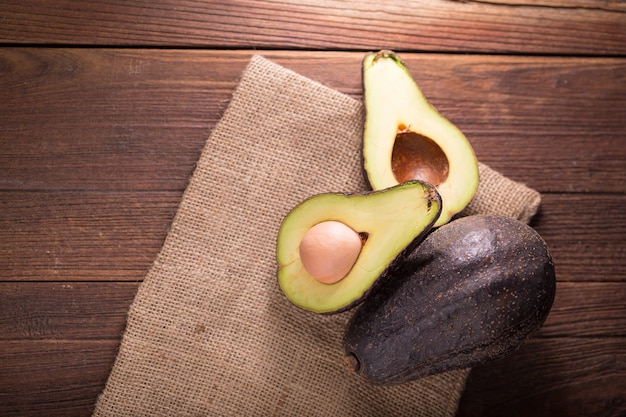 Gehalveerde avocado op een rustieke tafel. Verse avocado op zwarte achtergrond.