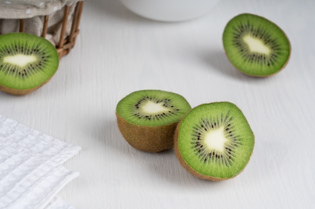 Gehalveerde rijpe groene plakjes kiwi fruit geserveerd op witte houten tafel met handdoek