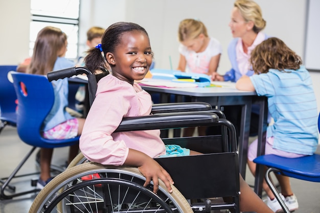 Gehandicapt schoolmeisje dat in klaslokaal glimlacht