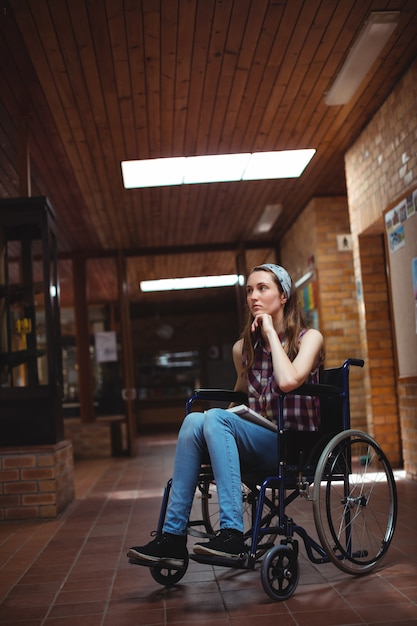 Gehandicapt schoolmeisje op rolstoel in gang op school