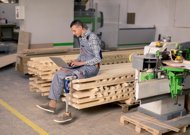 Gehandicapte jonge man met een kunstbeen werkt in de meubelfabriek