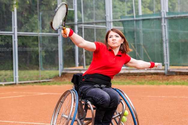 Gehandicapte jonge vrouw op rolstoel die tennis speelt op de tennisbaan