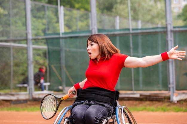 Gehandicapte jonge vrouw op rolstoel die tennis speelt op de tennisbaan