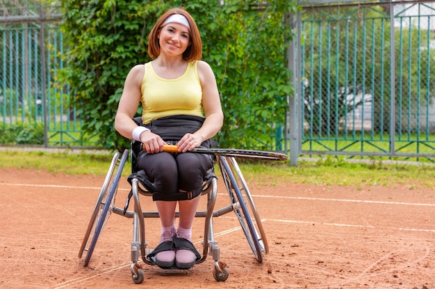 Gehandicapte jonge vrouw op rolstoel tennissen op tennisbaan.