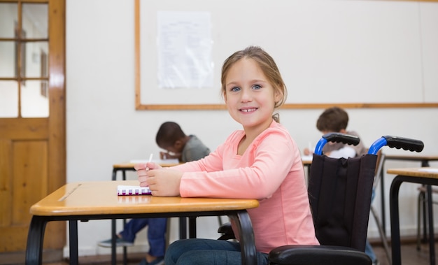 Gehandicapte leerling die bij camera in klaslokaal glimlacht