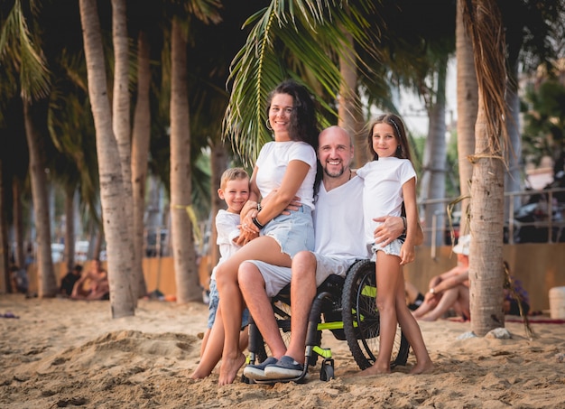 Gehandicapte man in een rolstoel met zijn familie op het strand.