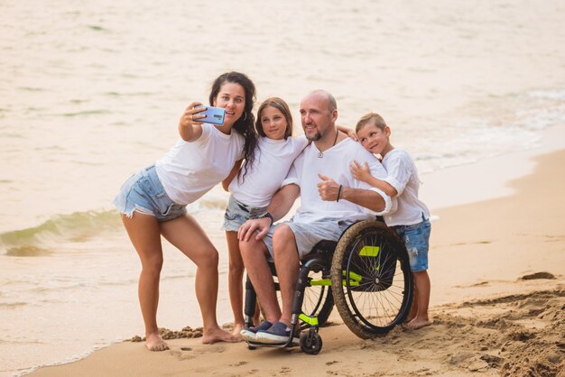 Gehandicapte man in een rolstoel met zijn familie op het strand.