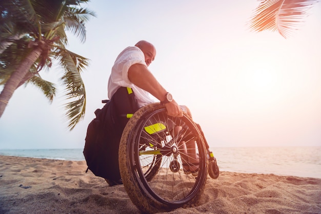 Gehandicapte man in een rolstoel op het strand.