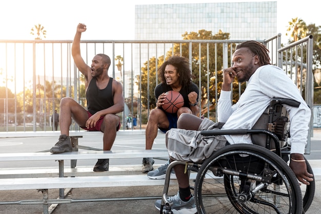 Gehandicapte man in rolstoel met zijn vrienden op een basketbalveld