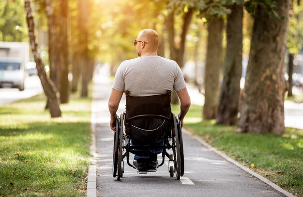 Gehandicapte man in rolstoelwandeling bij het parksteeg
