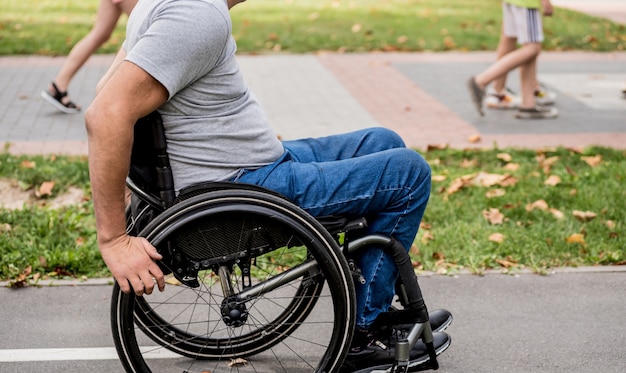 Gehandicapte man in rolstoelwandeling op het steegje van het park