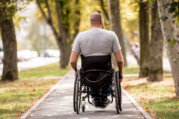 Gehandicapte man in rolstoelwandeling op het steegje van het park