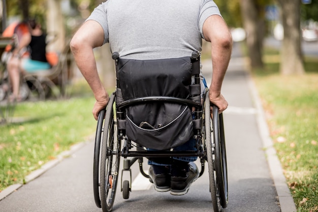 Foto gehandicapte man in rolstoelwandeling op het steegje van het park