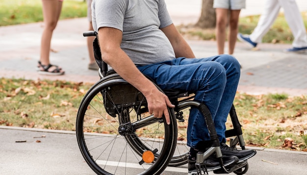 Gehandicapte man in rolstoelwandeling op het steegje van het park